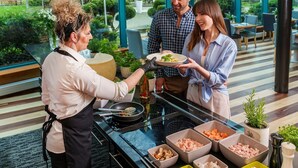 A restaurant with a modern interior, a glass dining area, and a variety of food ingredients on the counter. - Hotel Villa Park Med & Spa (Ciechocinek)