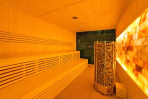 Una sauna con bancos de madera y un calentador de sauna instalado en la pared.
