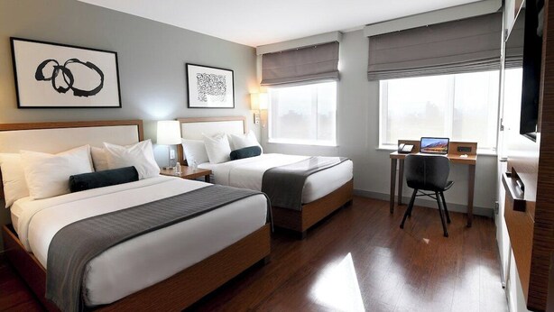 Una habitación de hotel con dos camas, un escritorio, una silla y un televisor.