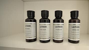 Four bottles of Lather body wash, moisturizer, and creme rinse on a shelf.