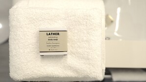 Toalla blanca con etiqueta que dice 'LATHER exfoliante corporal'.