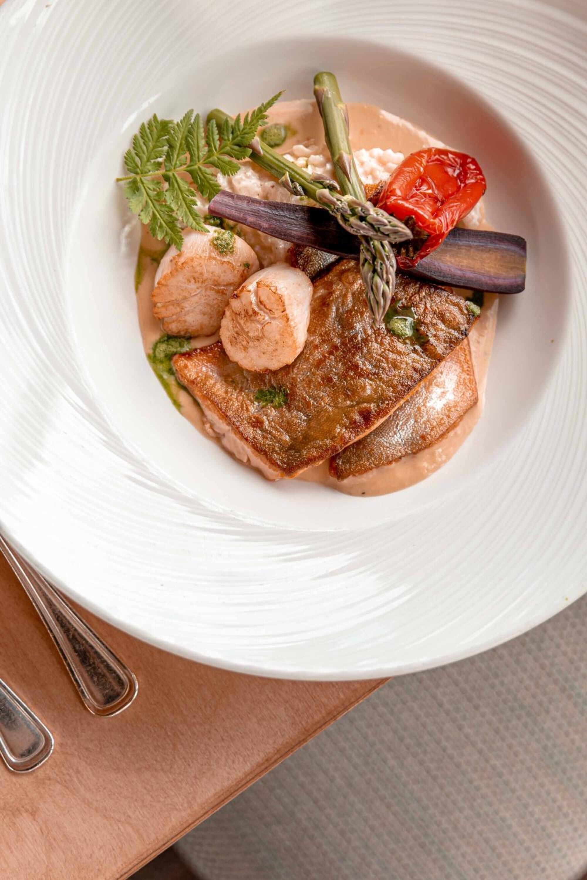 Une assiette blanche contenant un plat composé d’une portion de viande, de légumes et d’une garniture.