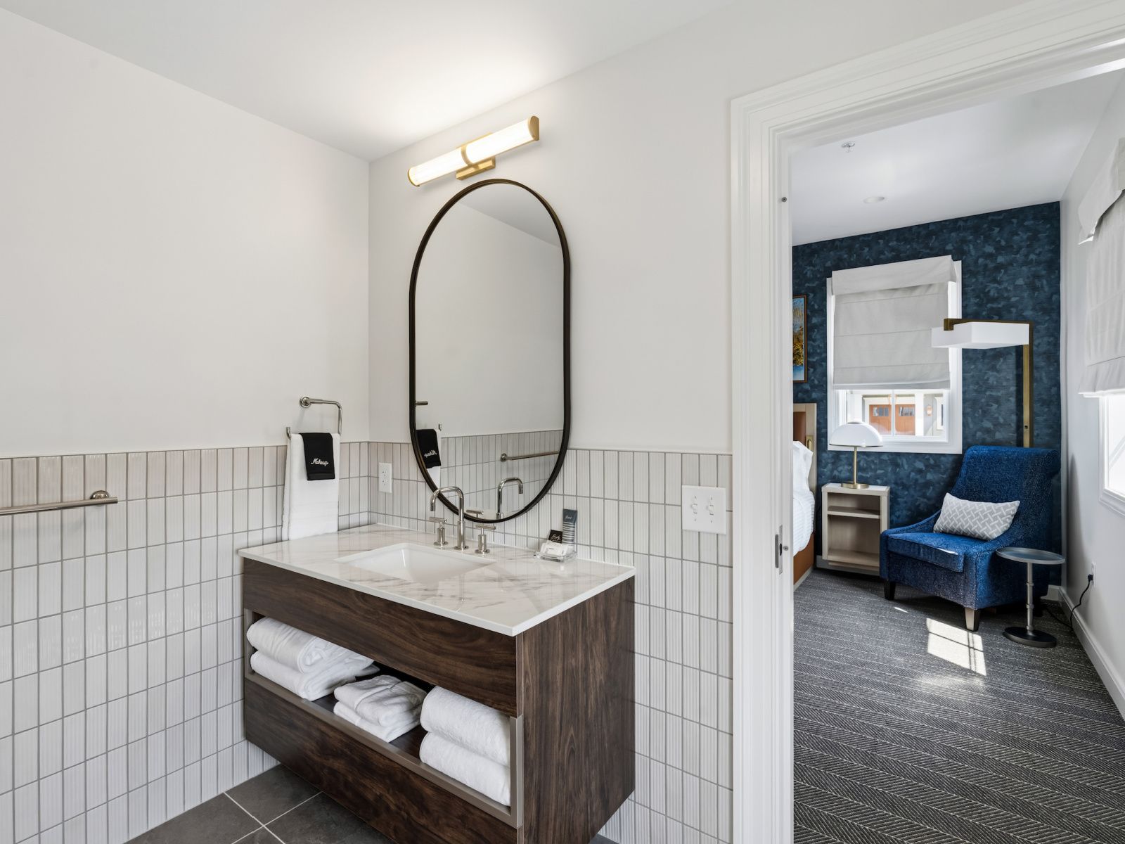 Une salle de bain moderne avec un grand miroir, un meuble-lavabo en bois et un porte-serviettes.
