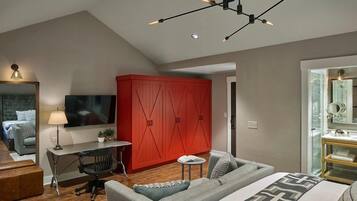 A modern bedroom with a bed, a desk, a red wardrobe, and a TV.