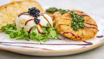 A plate with a poached egg, blackberries, and a breaded item with greens and sauce.