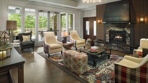 A spacious living room with a fireplace, comfortable seating, and large windows offering a view of the outdoors. - The Inn at Chesapeake Bay Beach Club (Stevensville)