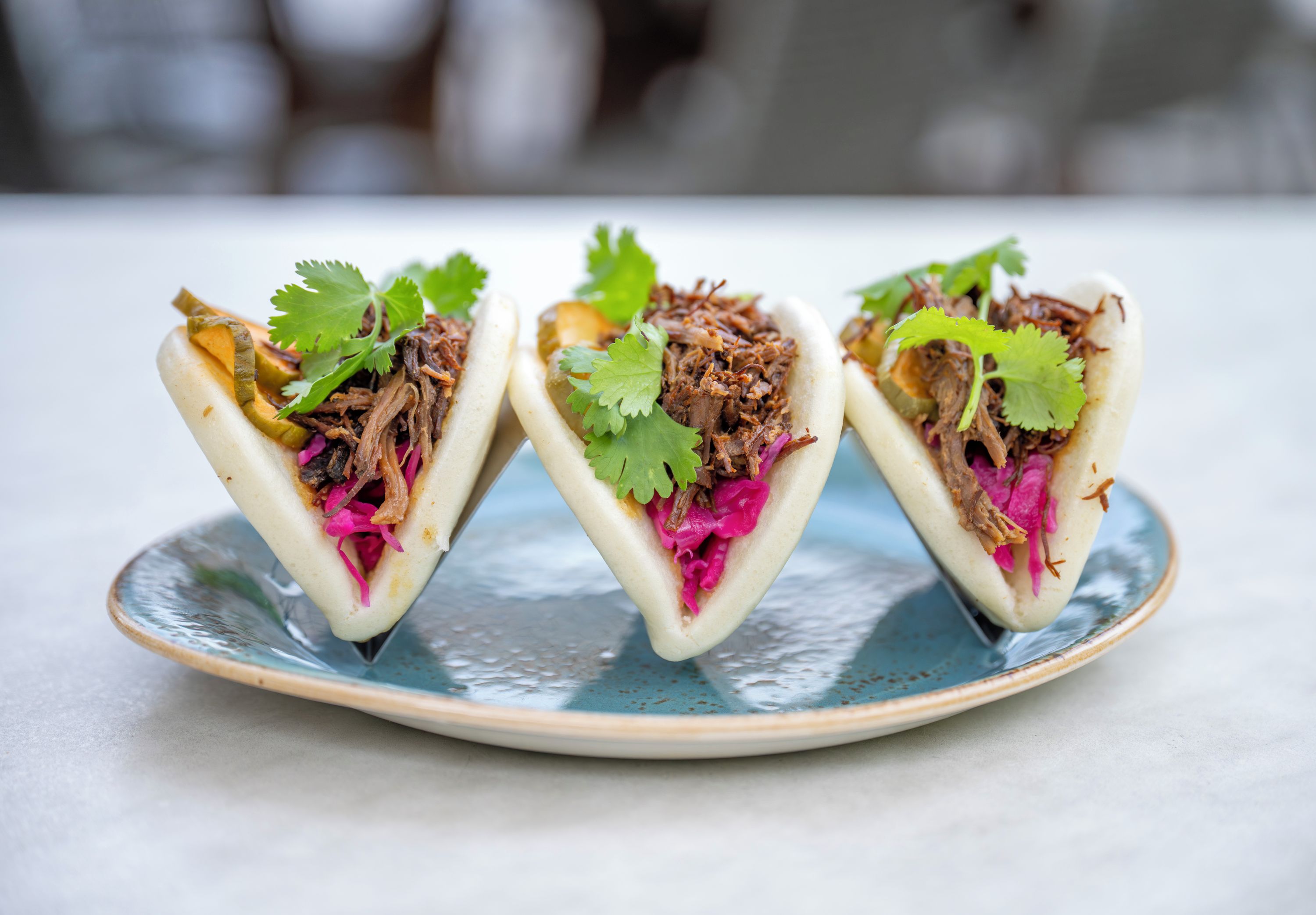 Tres tacos sobre un plato de cerámica.