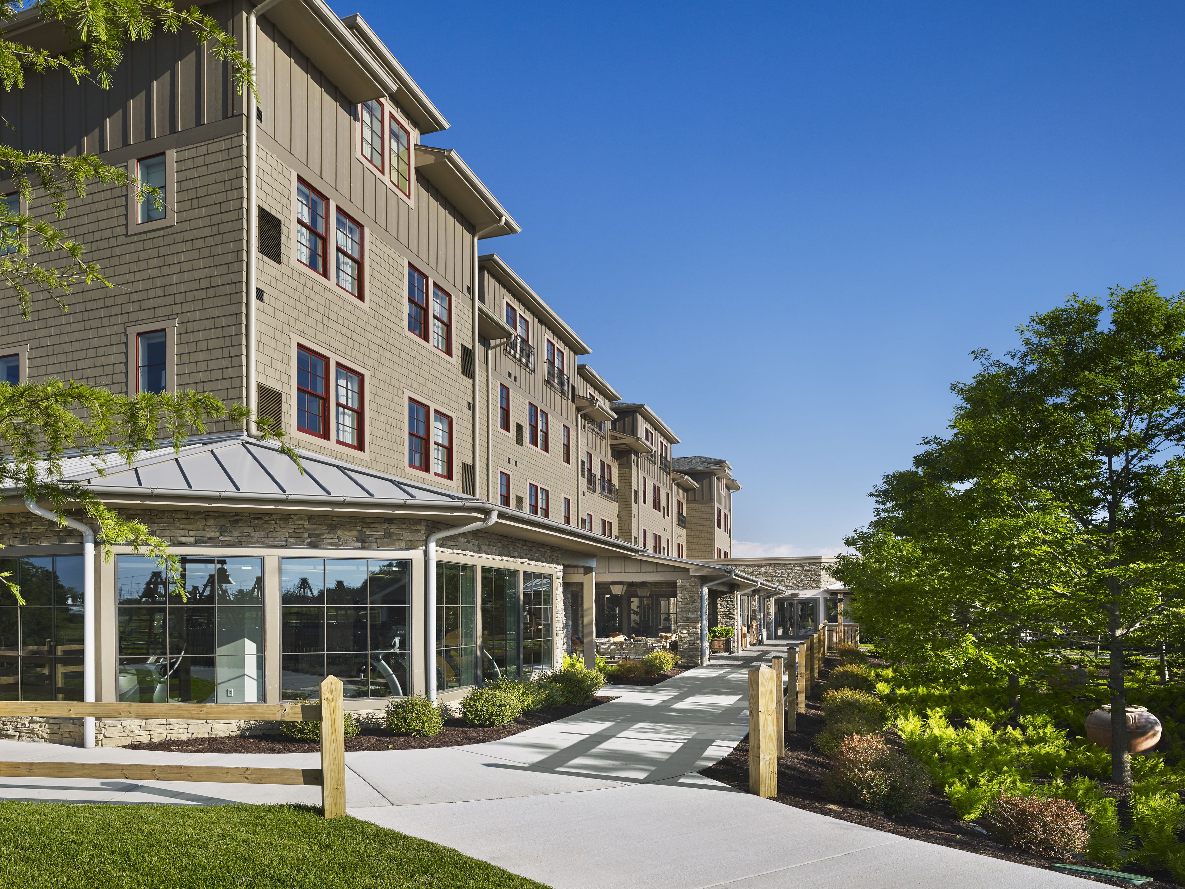 A multi-story residential building with a covered walkway and a landscaped garden.