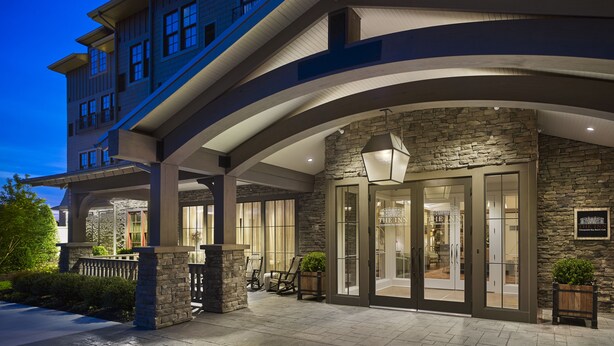A hotel entrance with a stone facade, large glass doors, and a sign indicating it is The Inn. - The Inn at Chesapeake Bay Beach Club (Stevensville)