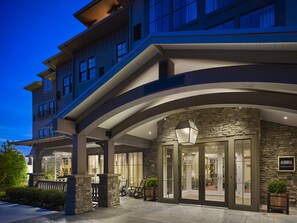 A hotel entrance with a stone facade, large glass doors, and a sign indicating it is The Inn. - The Inn at Chesapeake Bay Beach Club (Stevensville)