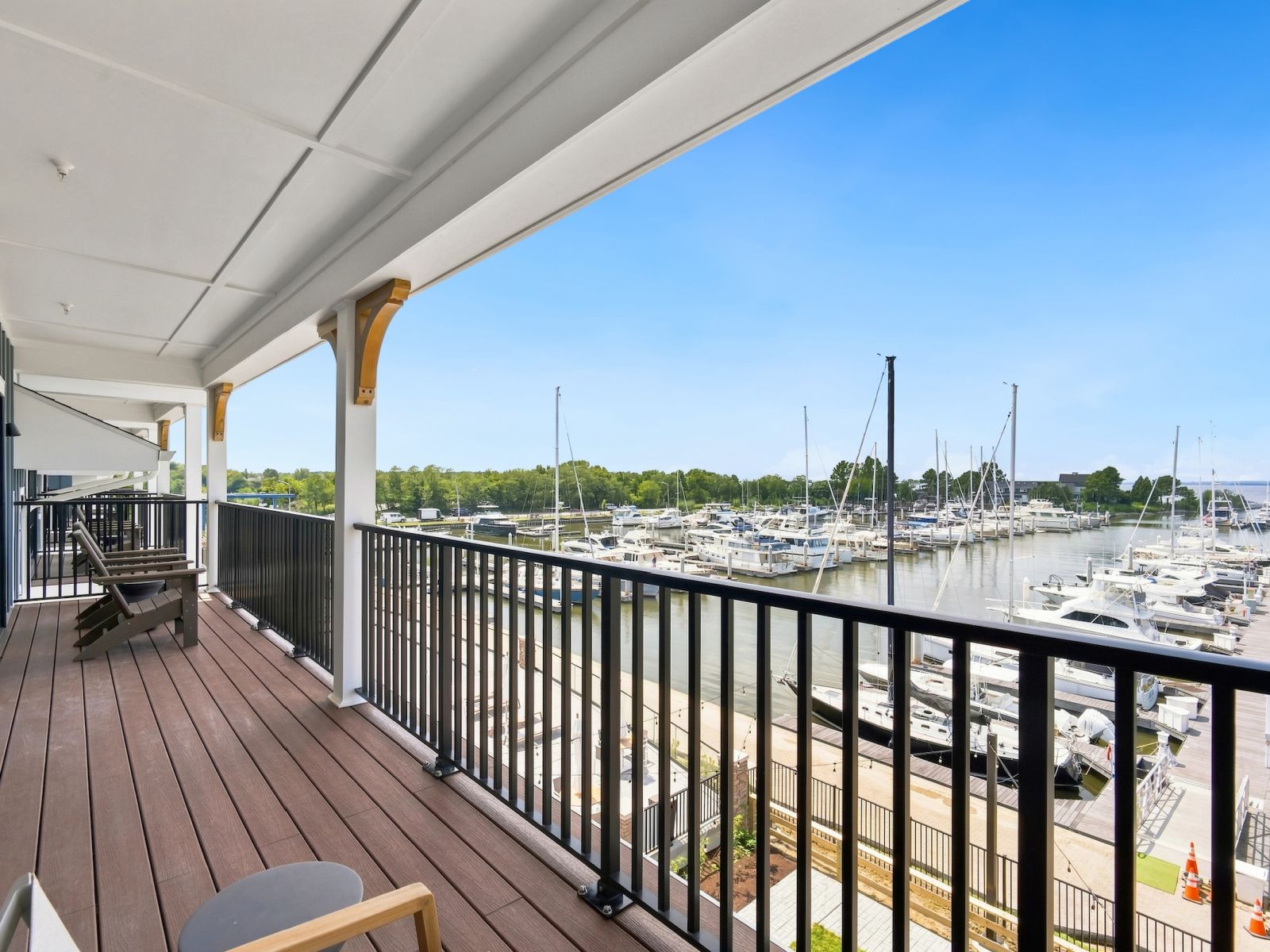 Un balcón con vista a un puerto deportivo, terraza de madera y mobiliario exterior.
