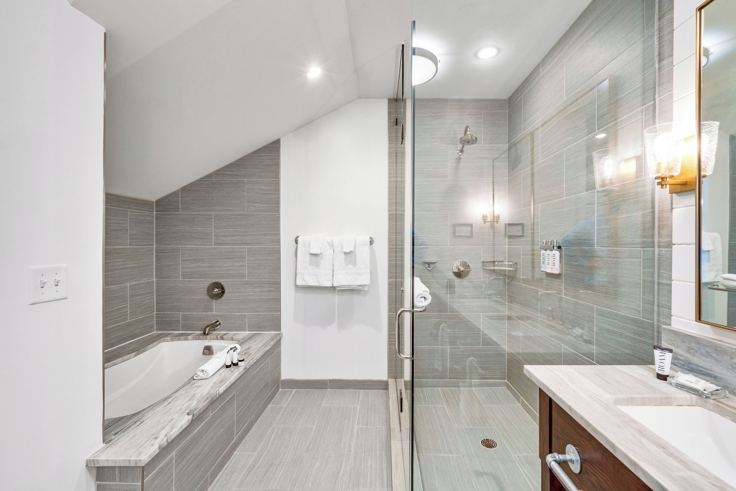 A modern bathroom with a glass-enclosed shower, a freestanding bathtub, and a vanity with a mirror.