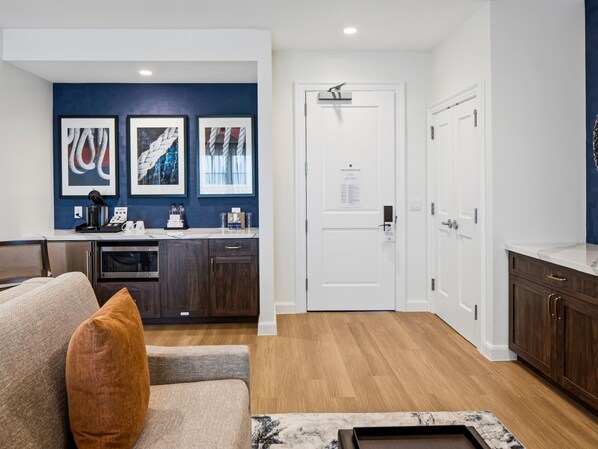 A modern living room with a sofa, a coffee table, and a kitchen area with a countertop and cabinets.