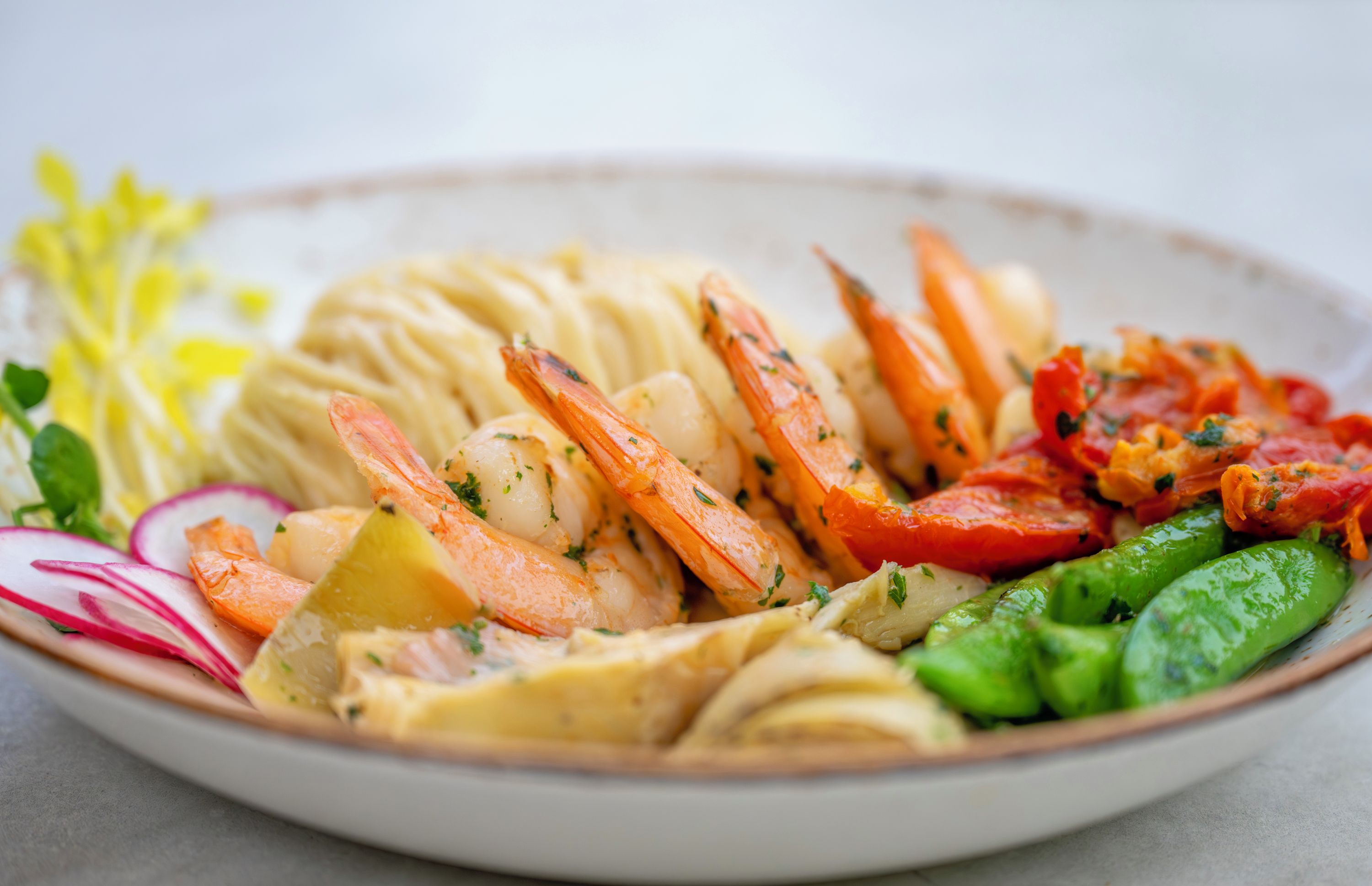 Une assiette de nourriture contenant des crevettes, des pommes de terre, des carottes et des légumes verts.