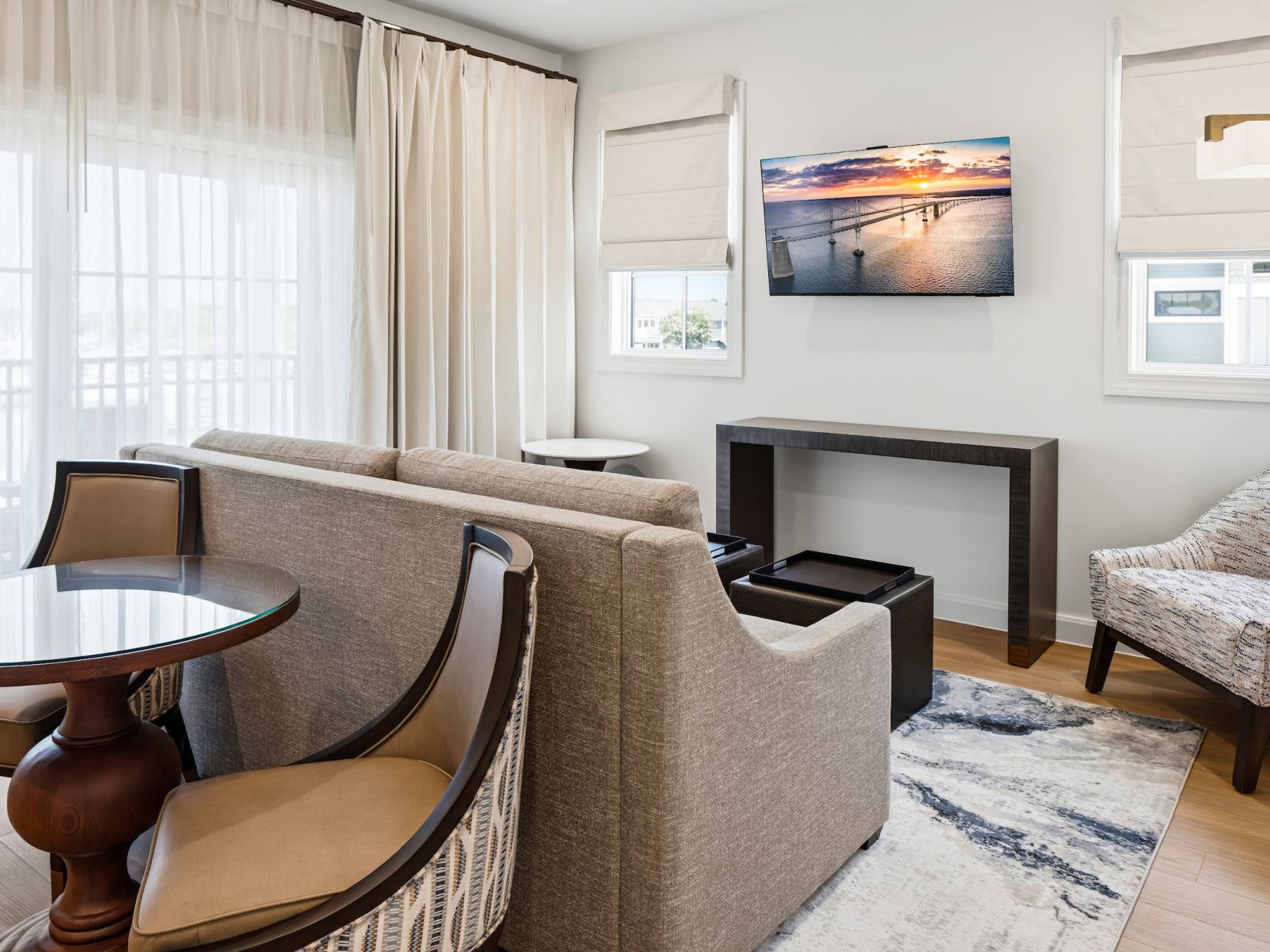 Un salon moderne comprenant un canapé, des fauteuils, une table basse, une cheminée et une grande fenêtre avec des rideaux.