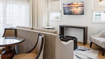 Un salon moderne comprenant un canapé, des fauteuils, une table basse, une cheminée et une grande fenêtre avec des rideaux.