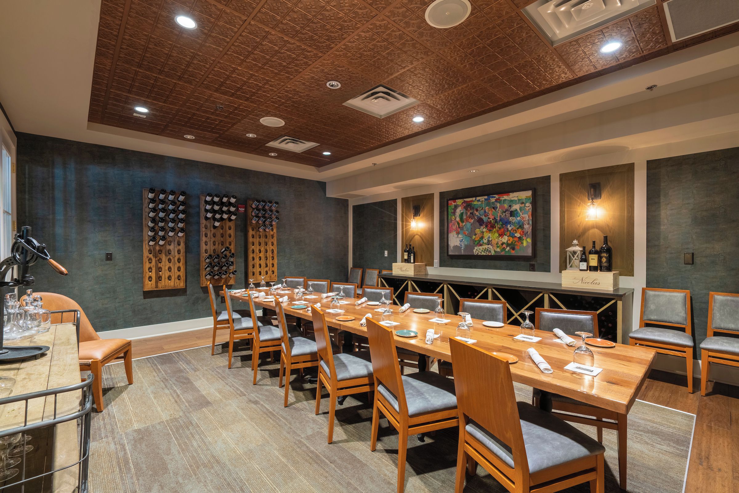 A conference room with a long wooden table, multiple chairs, and wine racks on the walls.