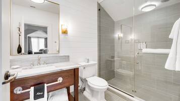 A modern bathroom with a glass-enclosed shower, a vanity with a mirror, and a toilet.