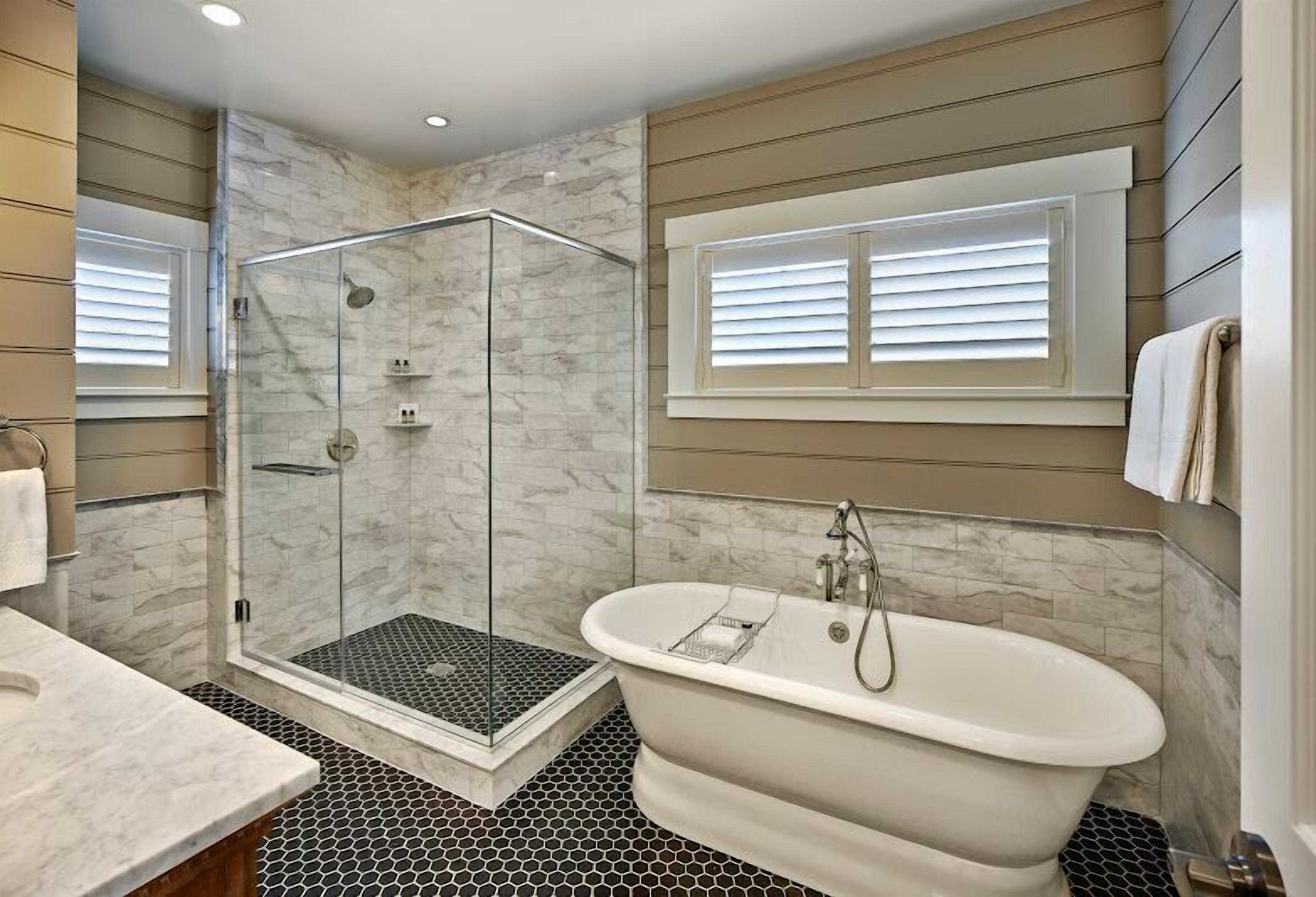 Un baño moderno con ducha de vidrio, bañera independiente y piso de baldosas.