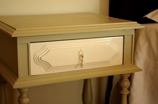 A small, cream-colored bedside table with a drawer, positioned against a wall. - Quinta Ponte da Capinha (Fundao)