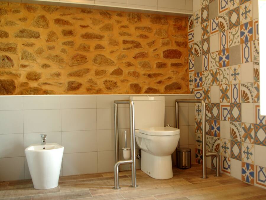 Un bagno con parete in pietra, un water, un bidet e un lavandino.