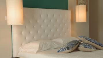 Un dormitorio con cabecera capitonada, ropa de cama blanca y almohadas decorativas.