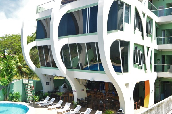 A modern hotel with a unique curved architecture, outdoor pool, and lounge area.