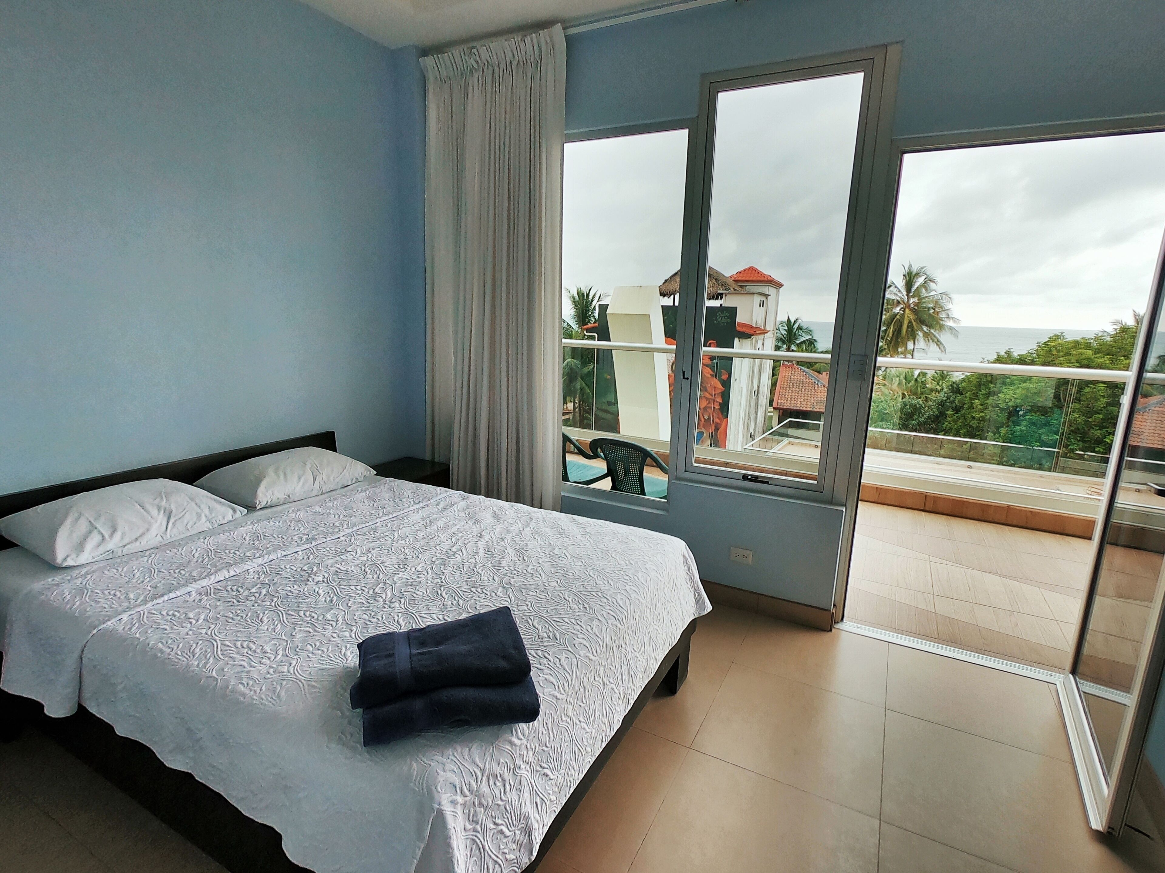 A bedroom with a bed, a window, and a view of the outside.
