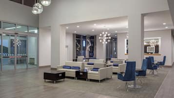 A modern lobby with seating areas, a reception desk, and a glass wall.
