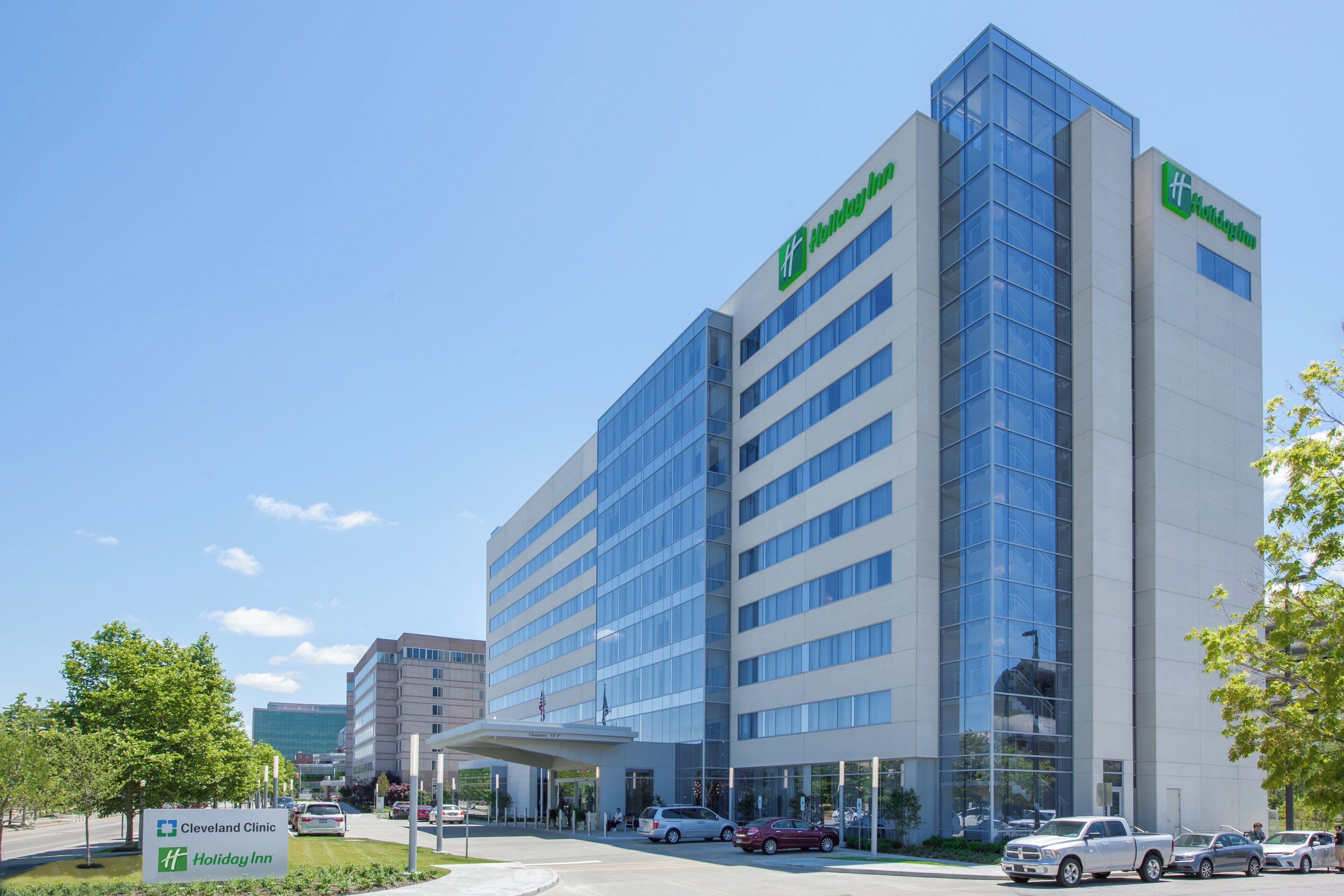 Un edificio moderno di un hotel con ingresso evidente, un'area parcheggio e un cartello del Cleveland Clinic nelle vicinanze.