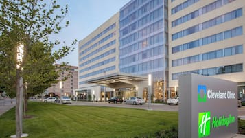 A Cleveland Clinic building with a Holiday Inn sign, surrounded by a well-maintained lawn and parked cars.
