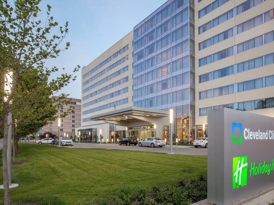 A Cleveland Clinic building with a Holiday Inn sign, surrounded by a well-maintained lawn and parked cars.