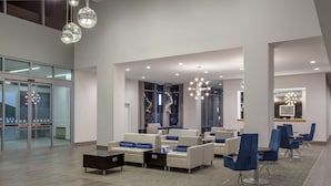 A modern lobby with seating areas, glass doors, and a staircase.
