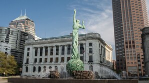 Un gran edificio clásico con una estatua de una mujer con un vestido ondeante.