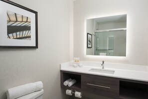A modern bathroom with a white sink, dark wooden vanity, a framed picture on the wall, and a large mirror above the sink. - Holiday Inn Cleveland Clinic by IHG (Cleveland)