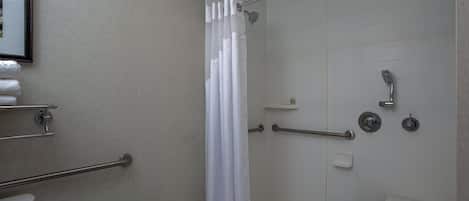 A modern bathroom with a walk-in shower, grab bars, a toilet, and a sink.