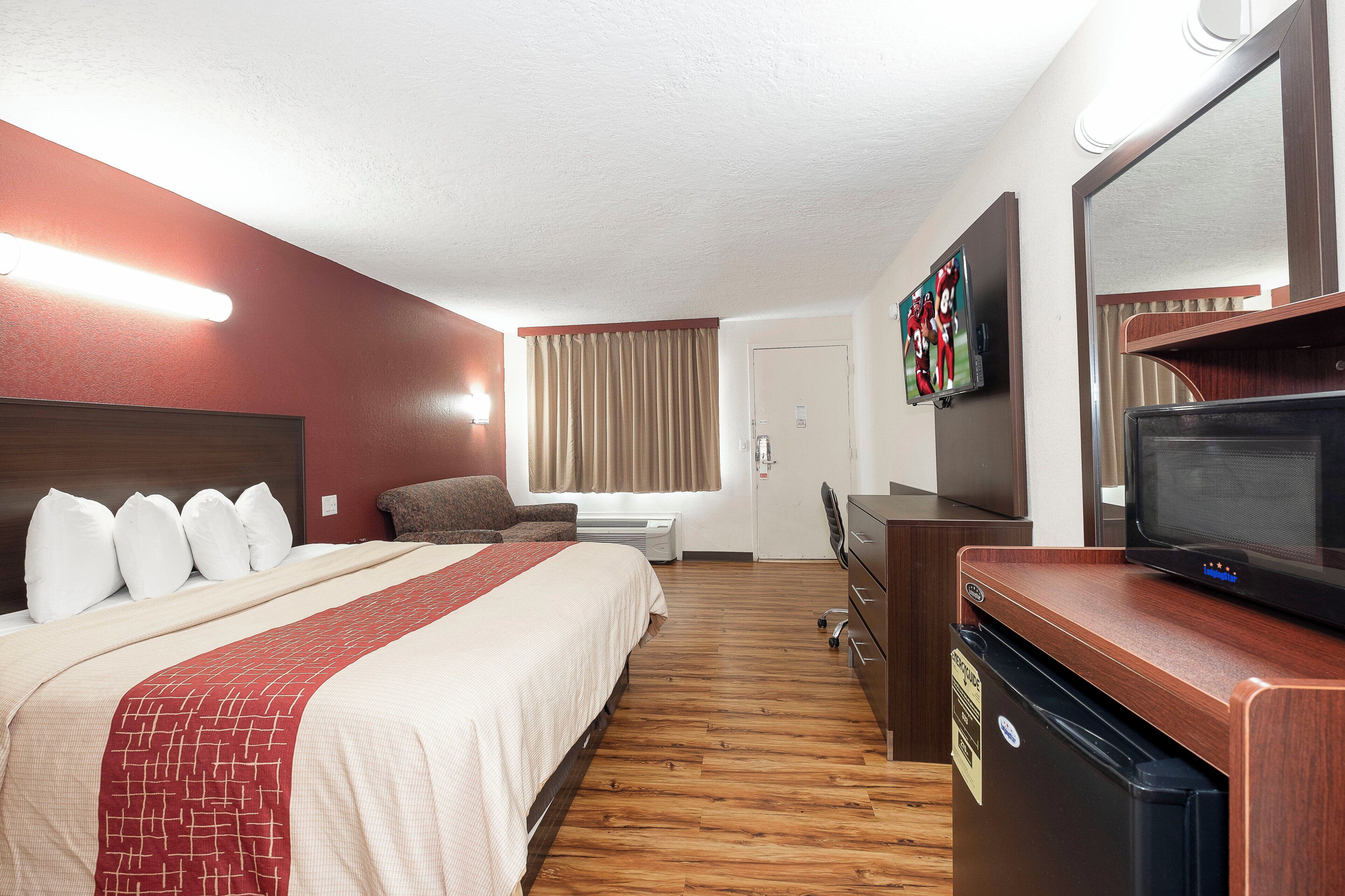 A hotel room with a bed, a desk, a television, and a minibar.