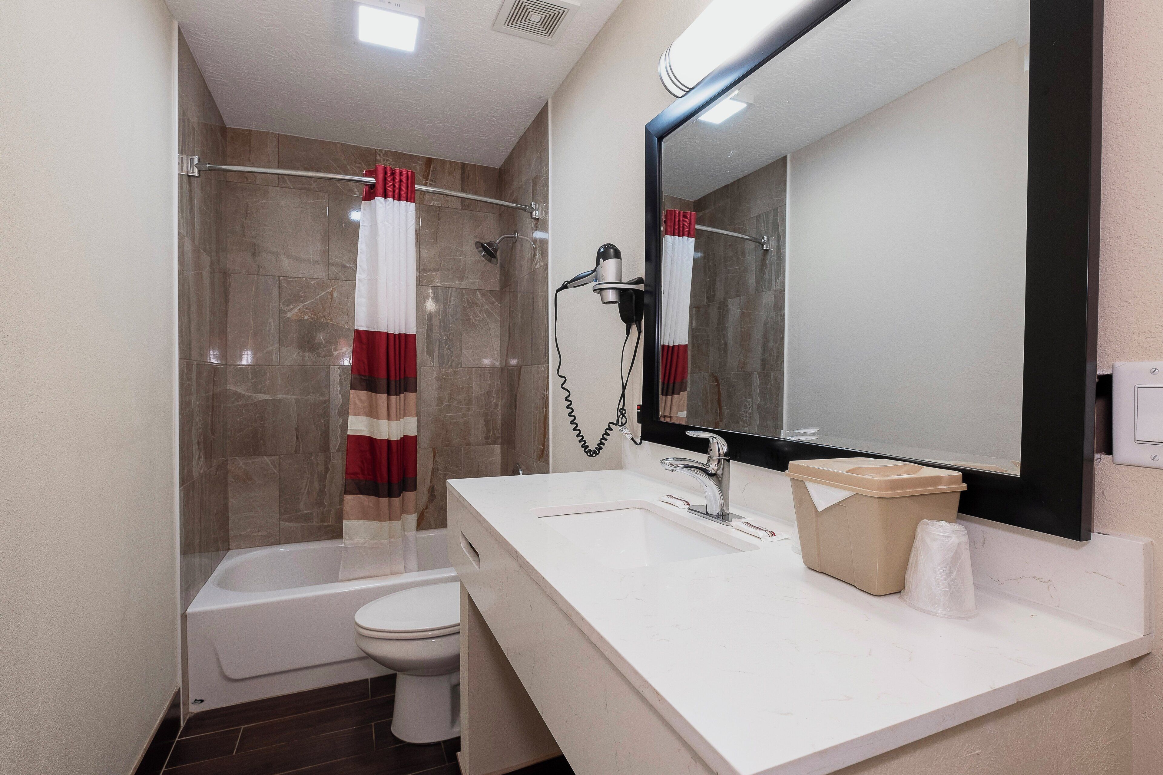 A bathroom with a bathtub, toilet, and a sink with a mirror above it.