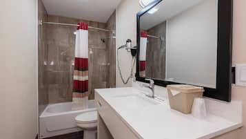 A bathroom with a bathtub, toilet, and a sink with a mirror above it.