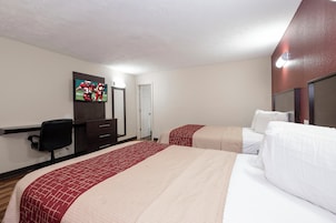A hotel room with two beds, a TV, a desk, and a chair.