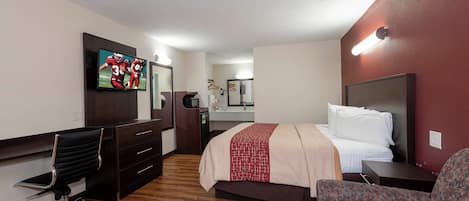 A hotel room with a bed, a desk, a chair, a television, and a mirror.