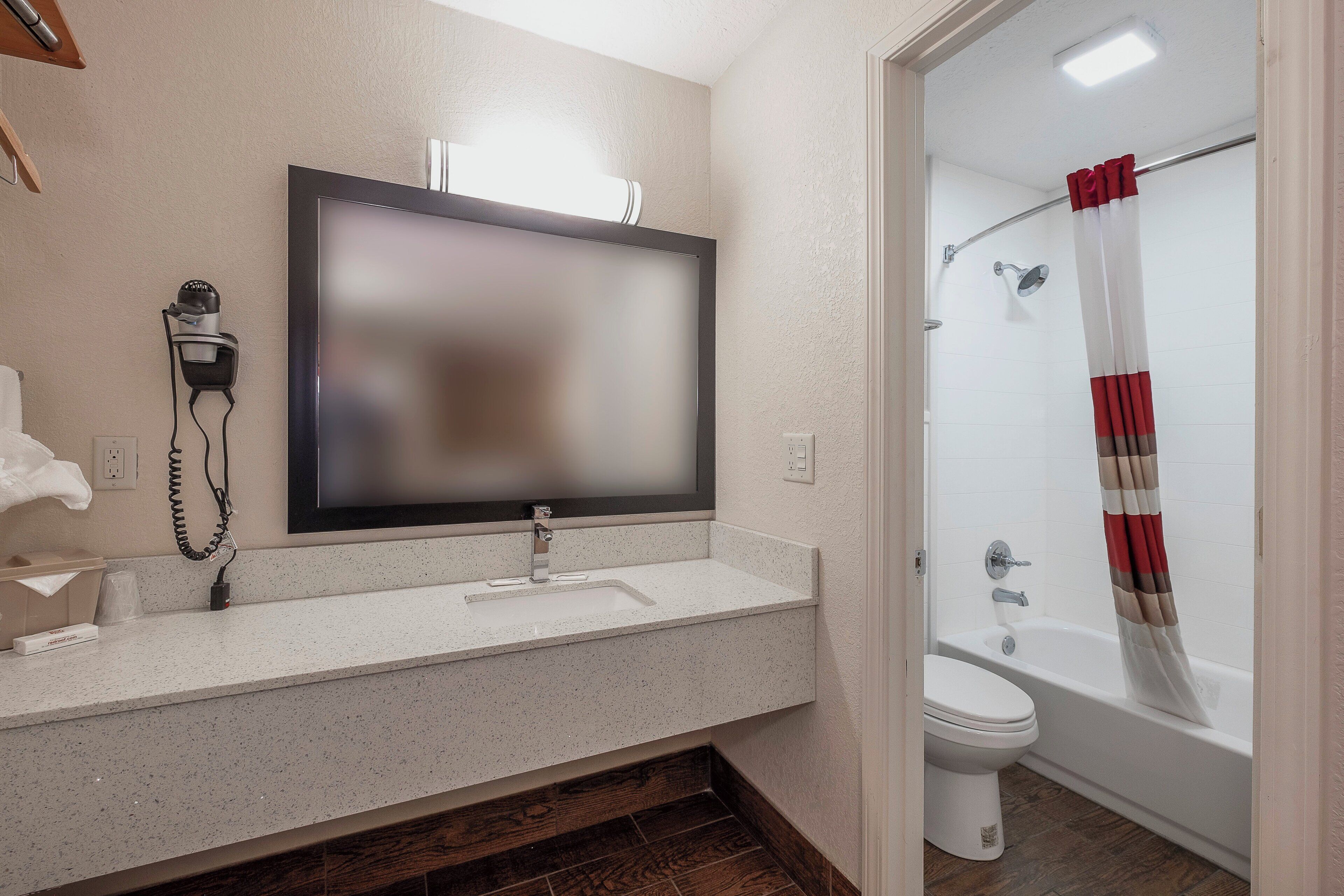 Une salle de bain équipée d’un lavabo, d’un miroir, d’un sèche-cheveux et d’un rideau de douche.