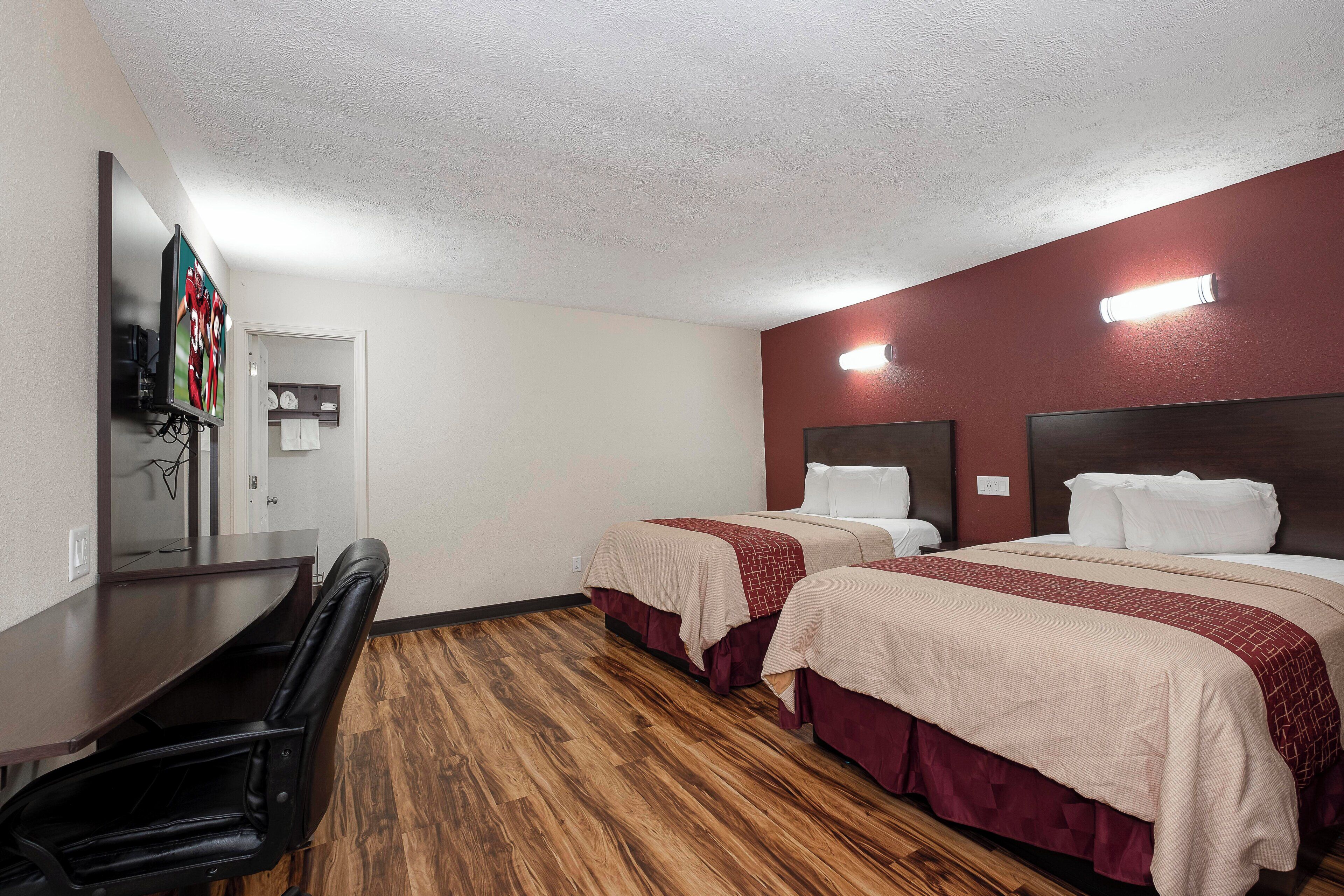 Habitación de hotel con dos camas, un escritorio y una silla.