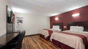 Habitación de hotel con dos camas, un escritorio y una silla.