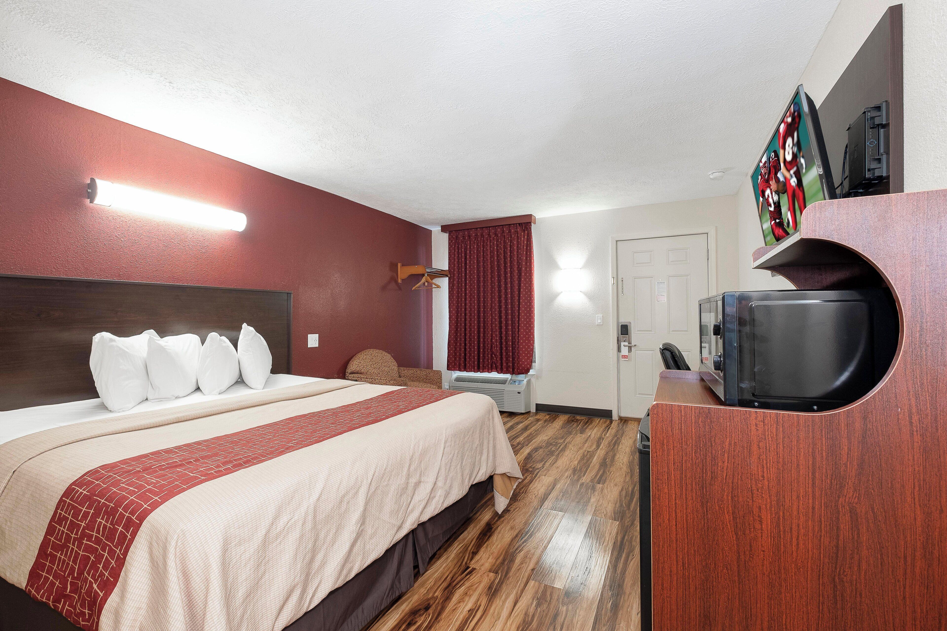 A hotel room with a bed, a TV, a coffee machine, and a door.