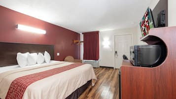 A hotel room with a bed, a TV, a coffee machine, and a door.