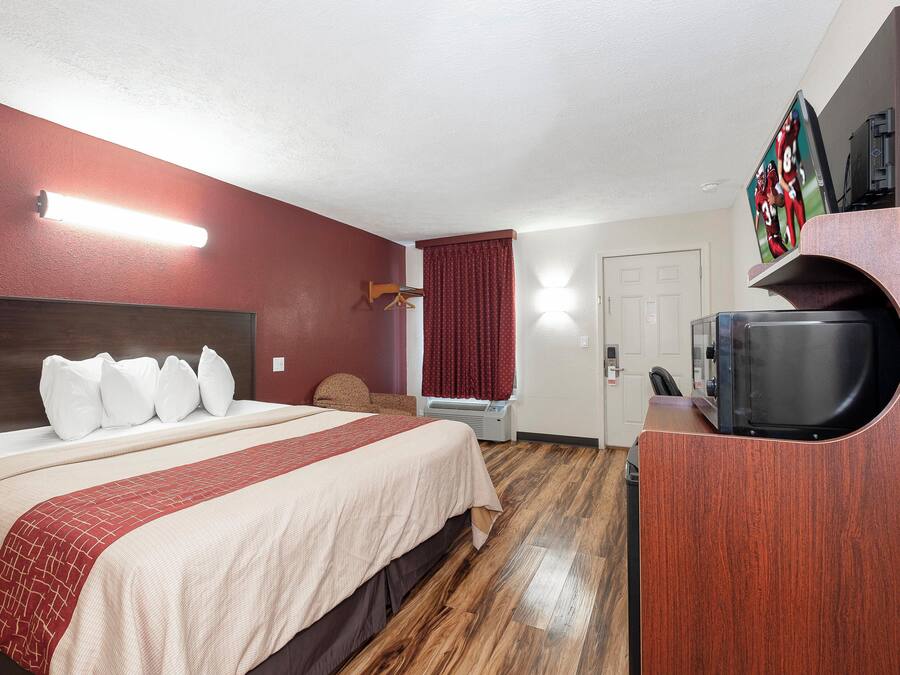 A hotel room with a bed, a TV, a coffee machine, and a door.