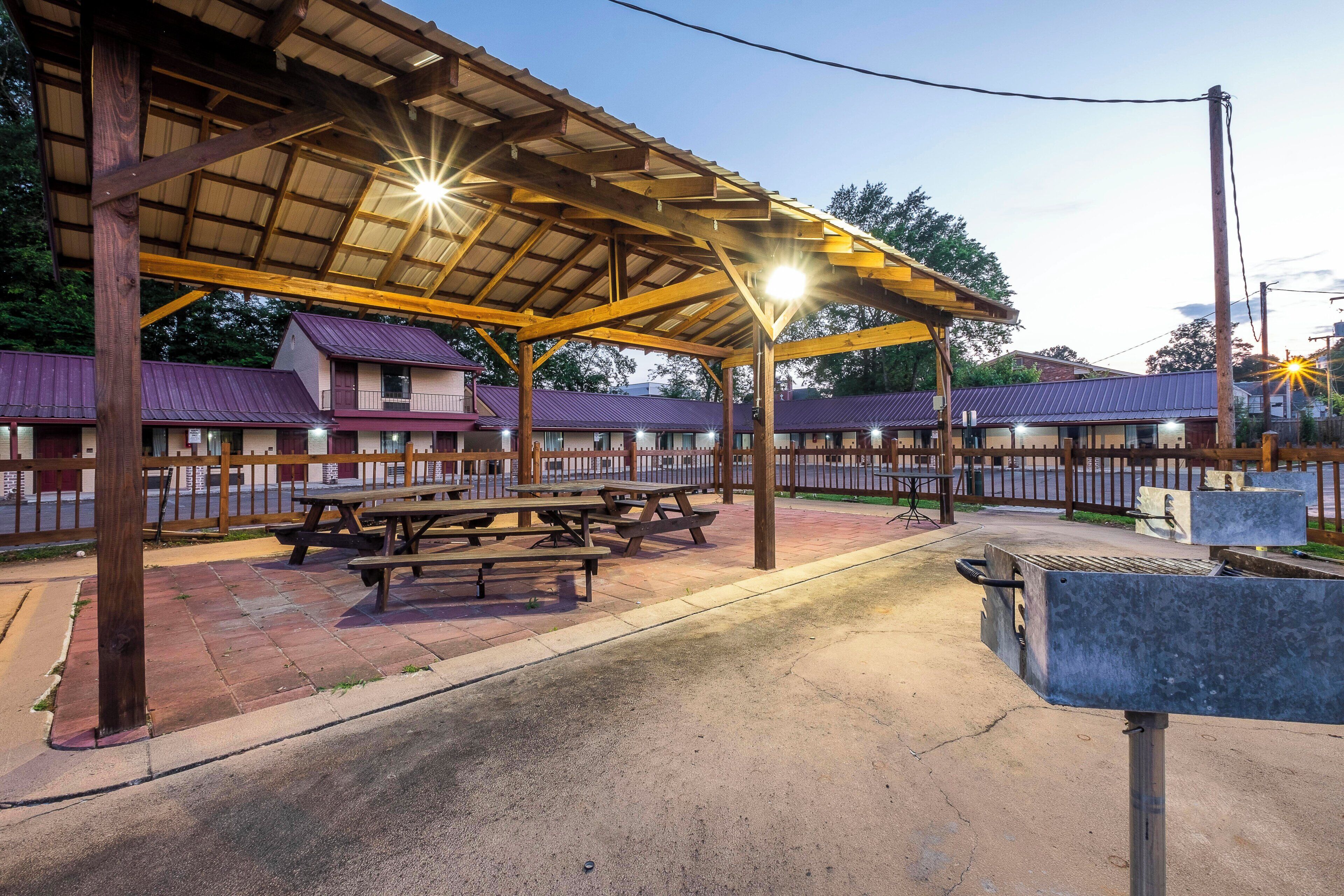 A covered outdoor seating area with picnic tables and a barbecue grill.