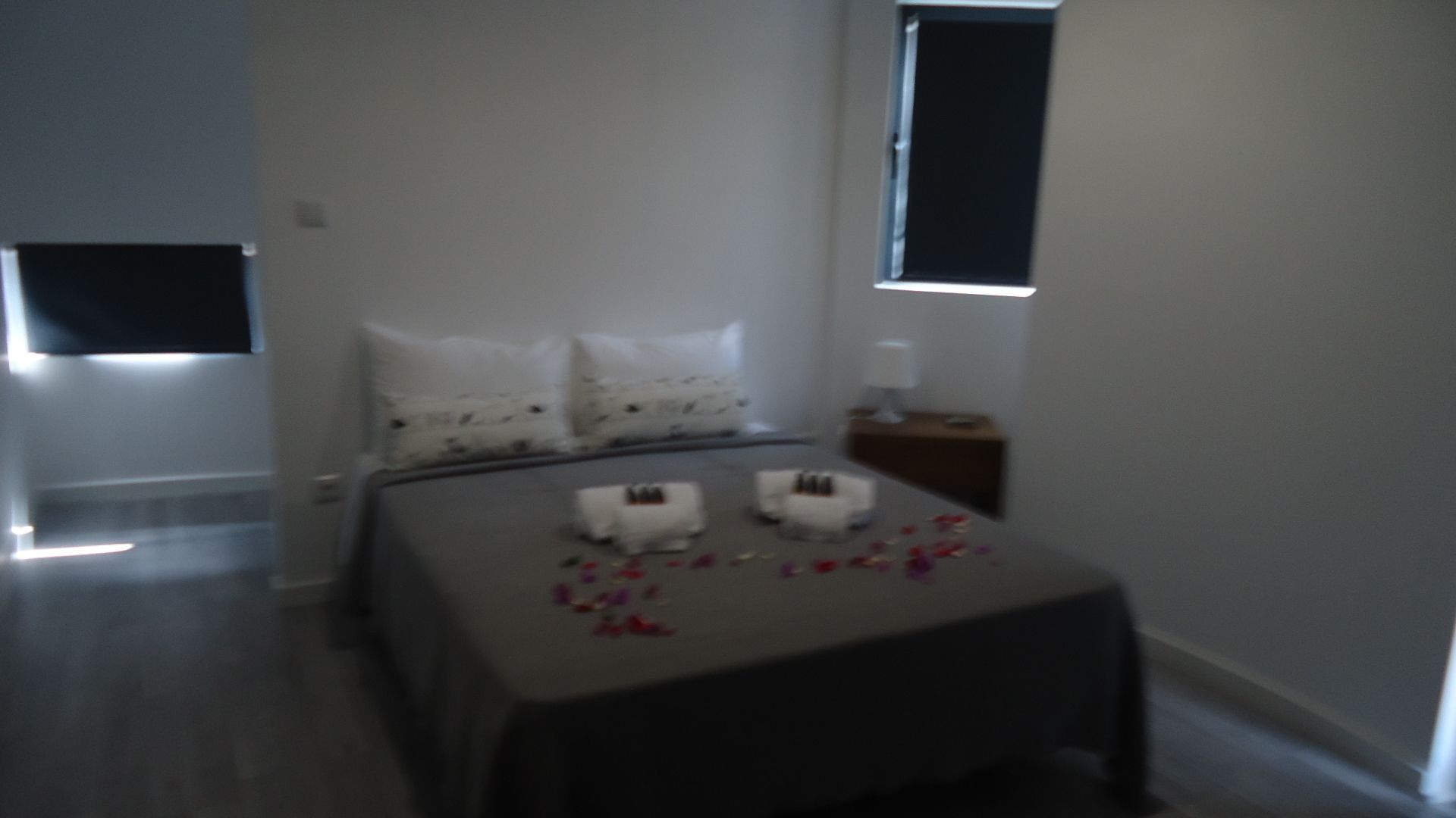Un dormitorio con cama, almohadas, una mesita de noche y una ventana.