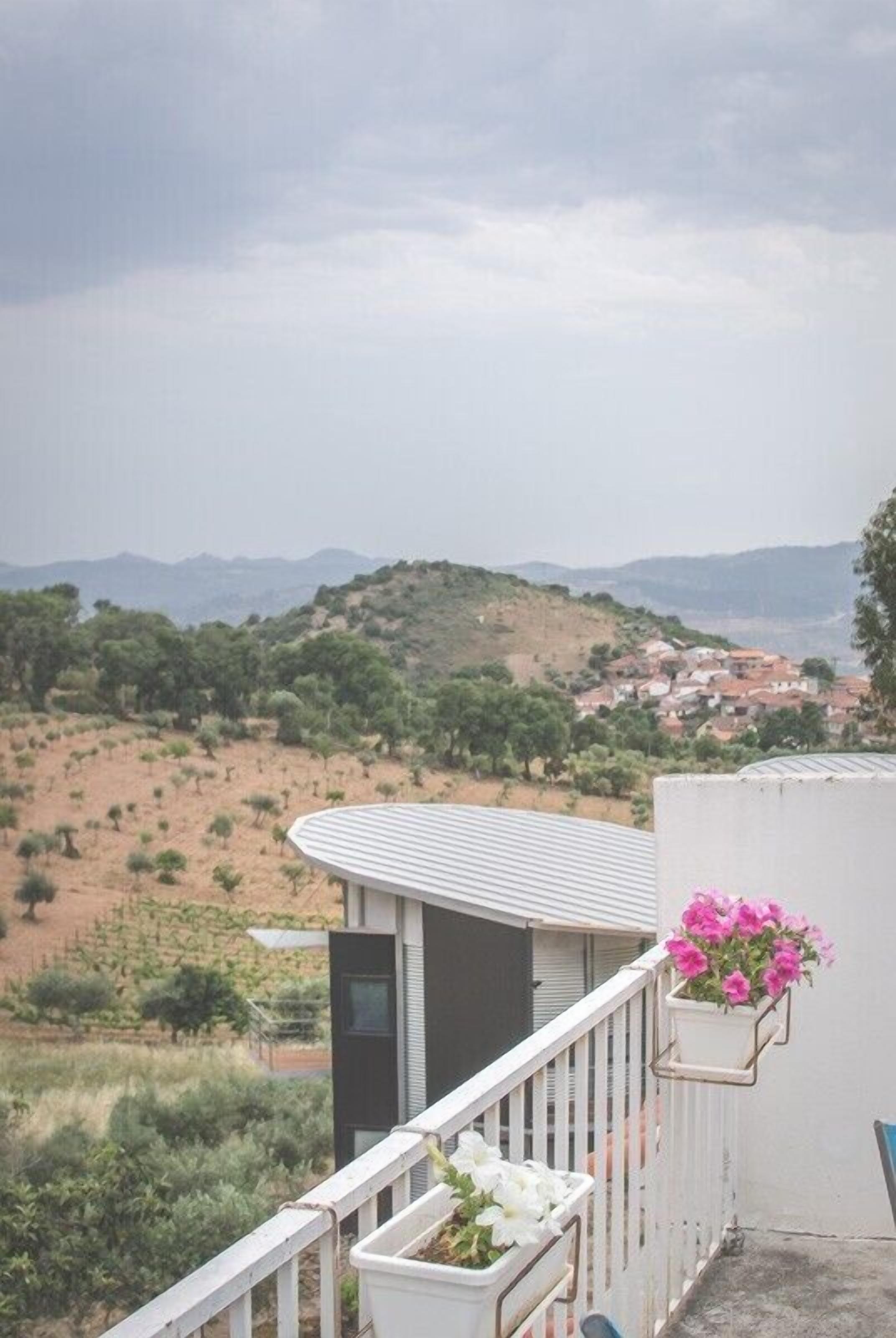 Un balcón con vista a un paisaje montañoso y un pueblo lejano.